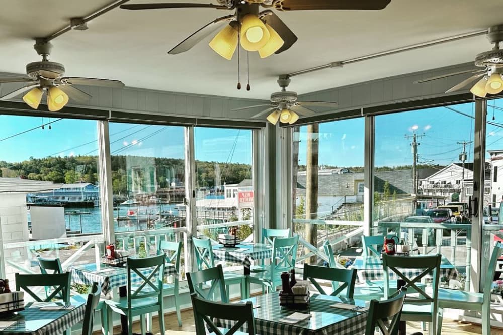 Cafe located at docks with teal dining chairs, checkered table cloths, amazing view, and ceiling fans to keep you cool.